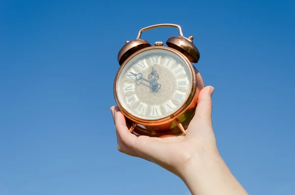 Часы римские цифры в руке на голубом фоне неба — стоковое фото