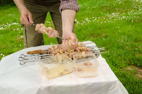 Człowiek umieścić mięso wieprzowe zielony szpikulec do gotowania na ognisku — Zdjęcie stockowe
