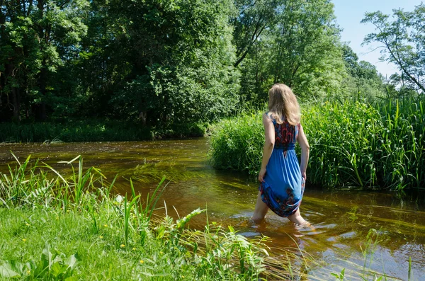 金髪の女の子の青まだらドレス ウェイドに流れる川 — ストック写真
