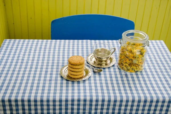 Getrocknetes Ringelblumengericht mit Tasse und Keksen auf dem Tisch — Stockfoto