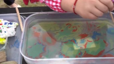 Ebru suda resim yapıyor. Antik Türk sanatı. Kızların elinde boya fırçası