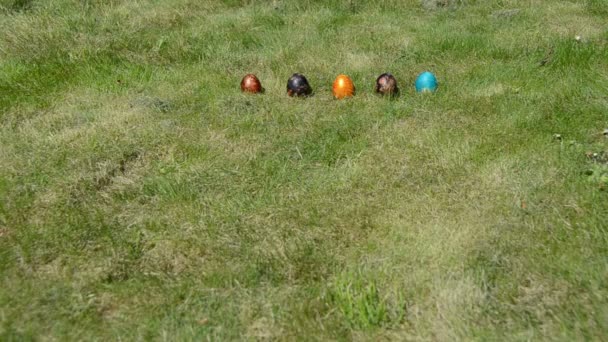 Jogo tradicional de Páscoa. Mão jogar rolar ovos coloridos na grama . — Vídeo de Stock