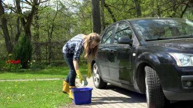 Kadın bahçede köpüklü süngerle siyah araba camını yıkıyor. 4K