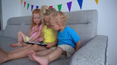 Hüsrana uğramış kızıl saçlı kız tablet bilgisayarla oynayan sarışın arkadaşına bakıyor. Olumsuz duygular. Titreşimli yumuşak kamera hareketi görüntüsü.