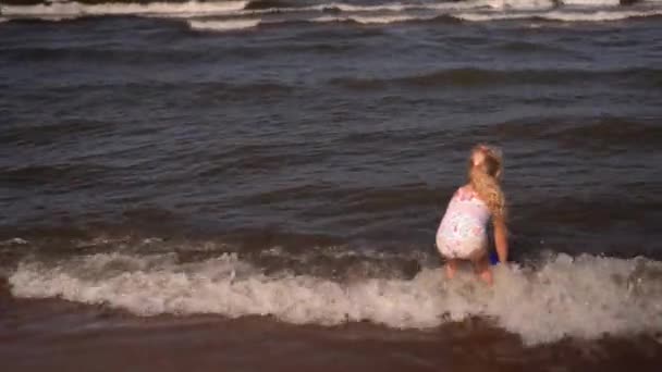 Menina pré-escolar colher água do mar com balde de brinquedo e transportar. — Vídeo de Stock