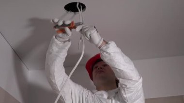 Özel kıyafetli bir adam penseyle kablo kesti. Yeni dairede aydınlatma. 4K