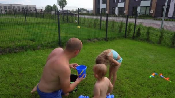 Padre giocoso versare acqua sui suoi figli carino figlia e figlio con secchio giocattolo — Video Stock