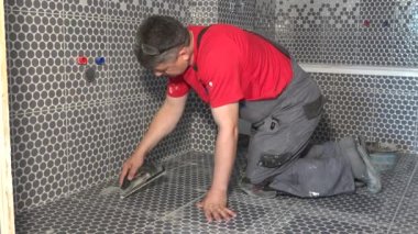 Tiler adam kiremitler arasındaki boşlukları harçla dolduruyor.