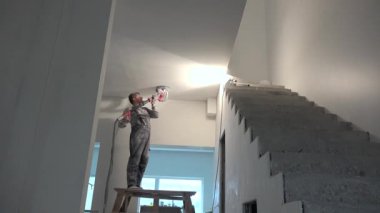 İnşaat alanında tavanı cilalayan öğütücü makineli inşaat işçisi.