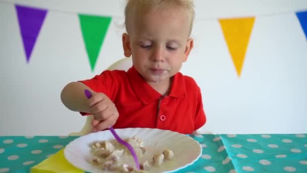 Brudny chłopak jedzący pierogi przy stole. Ruch gimbalny — Wideo stockowe