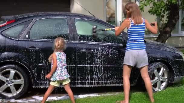 母親と娘は父親の車を洗う。家族の女の子はパパのために驚きを準備. — ストック動画