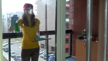 Kadın balkondaki kirli pencereye köpük püskürtüyor. Mevsimlik iş. 4K