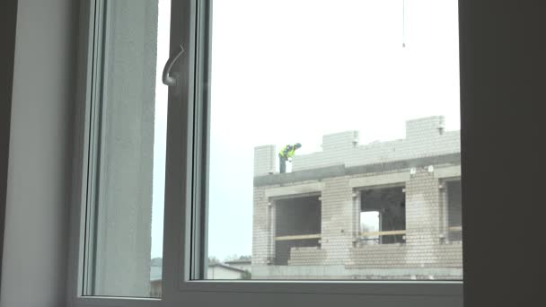 Stavební průmysl. Dělníci staví dům z bílých cihel. Zobrazení okna. — Stock video