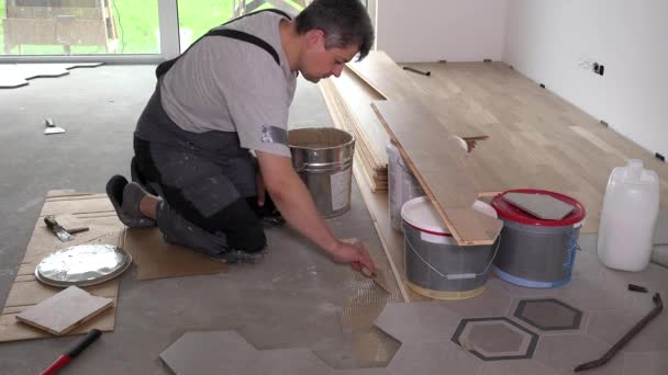 Trabalhador aplicar cola adesiva no chão para colocação de placa de parquet — Vídeo de Stock