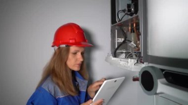 Tablet bilgisayarlı kadın mühendis gaz ısıtma sistemini onarıyor