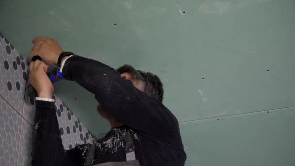 Elinde tornavida olan adam tavan alçıtaşı çarşaflarını tamir ediyor. — Stok video