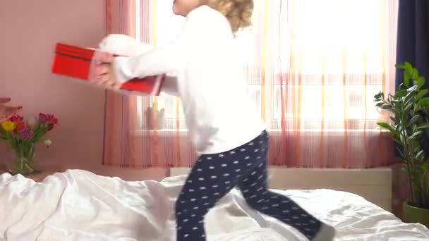 Мила дівчина біжить з подарунком матері в ліжко. Мама задоволена подарунком дочки. 4-кілометровий — стокове відео