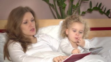 Genç anne, evdeki tatlı küçük kızına masal okuyor. Annelik ve çocukluk. 4K