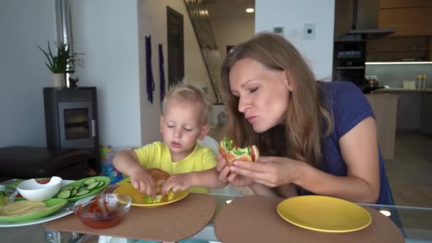 妈妈和她好奇的儿子在家里吃汉堡包 投篮相机移动射击 — 图库视频影像