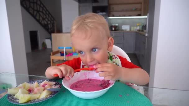 Poważne Dziecko Jedzące Zupę Buraczaną Siedzące Wysokim Krześle Przy Stole — Wideo stockowe