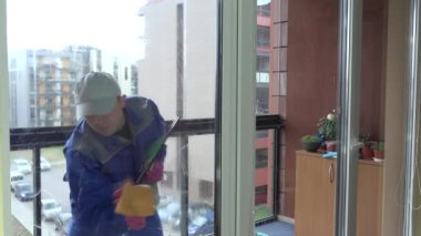 worker man clean dirty glass window with foam and wiper brush in balcony. 4K