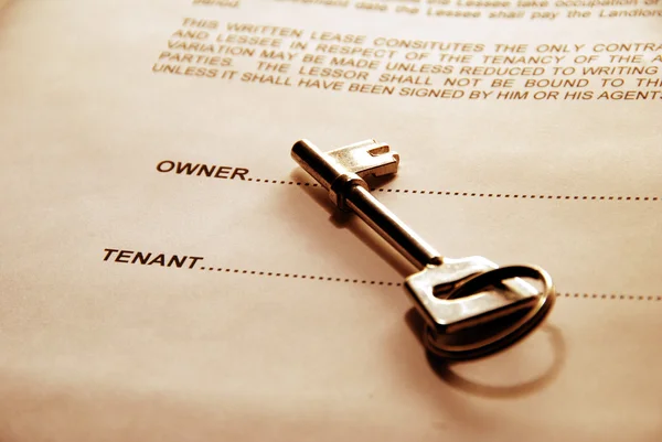 Key lying on a lease document — Stock Photo, Image