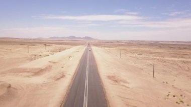 Çölde koşan bir yolun üzerinden geçen hava manzarası.