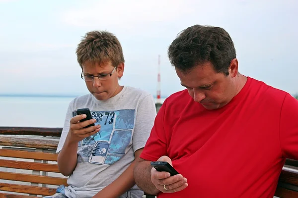 Мужчина и мальчик с мобильными телефонами — стоковое фото