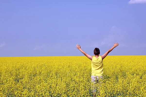 Feliz adolescente de pie en un campo de colza oleaginosa Imagen De Stock