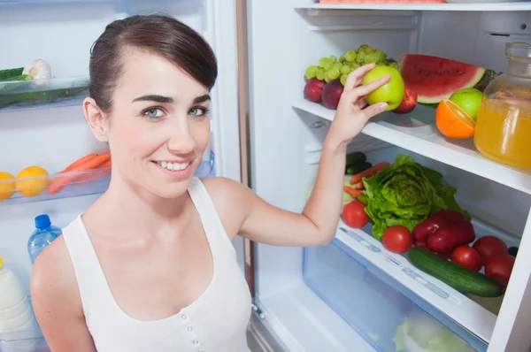 Jovem mulher tirando maçã da geladeira — Fotografia de Stock