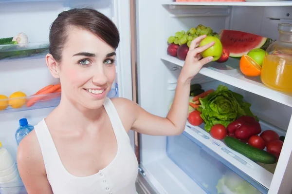 Mujer joven sacando manzana de la nevera — Foto de Stock