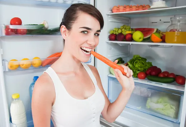 Mujer joven sacando jugo de zanahoria de la nevera — Foto de Stock