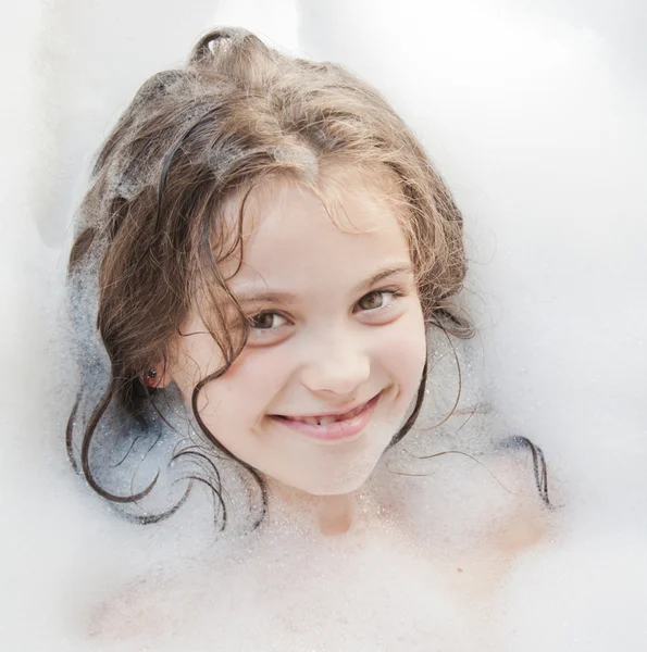 Piccola bella ragazza sta facendo un bagno con una schiuma — Foto Stock