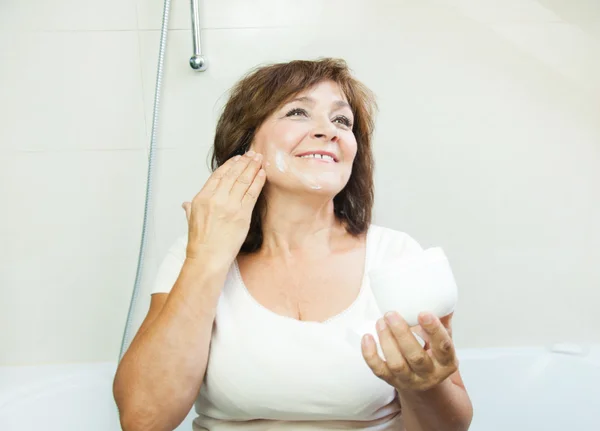 Mulher sênior bonita aplicando creme no banheiro — Fotografia de Stock