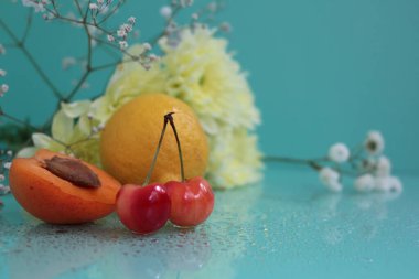 Composition of fresh fruits and flowers on a turquoise background