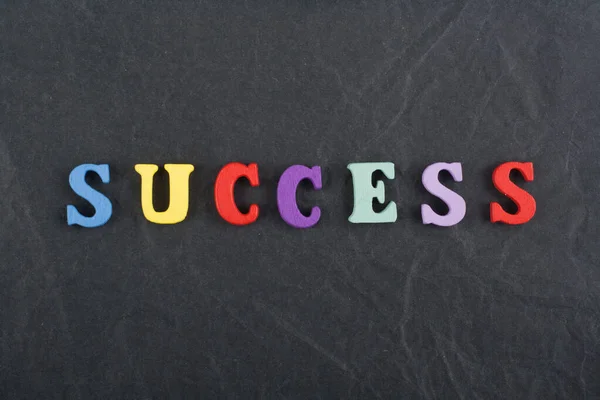 SUCCESS word on black board background composed from colorful abc alphabet block wooden letters, copy space for ad text. Learning english concept. — Stock Photo, Image