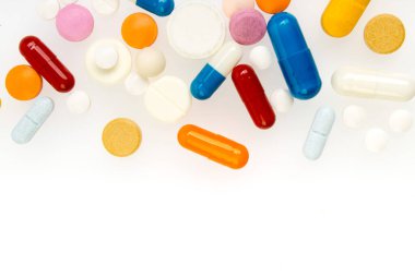 Beyaz arka planda izole edilmiş farklı renkli haplar ve kapsüller.