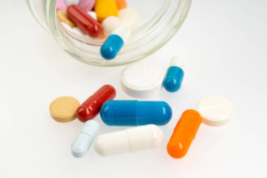 Beyaz arka planda izole edilmiş farklı renkli haplar ve kapsüller.