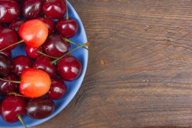Çeşitli taze kiraz bir kase rustik ahşap masa üzerinde yaz. Antioksidan, detoks diyet, organik meyve.
