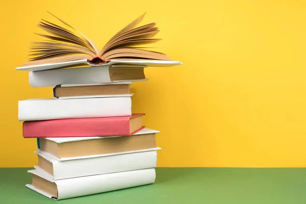 Book stacking. Open hardback books on wooden table and green background. Back to school. Copy space for ad text