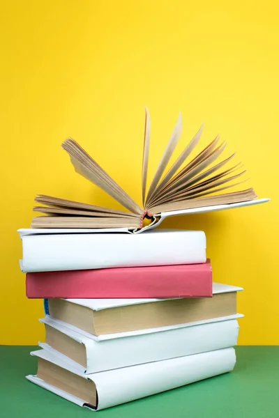 Book stacking. Open hardback books on wooden table and green background. Back to school. Copy space for ad text