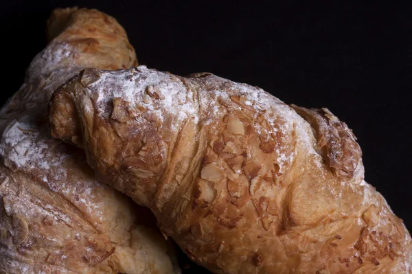 Frisches Mandelcroissant auf schwarzem Hintergrund — Stockfoto