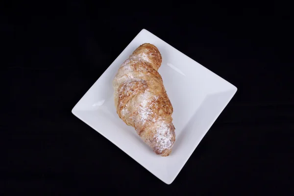 Croissant de amêndoa fresca em um fundo preto — Fotografia de Stock