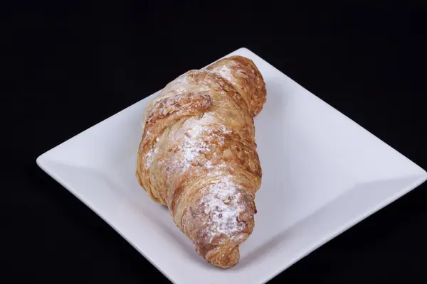 Frisches Mandelcroissant auf schwarzem Hintergrund — Stockfoto