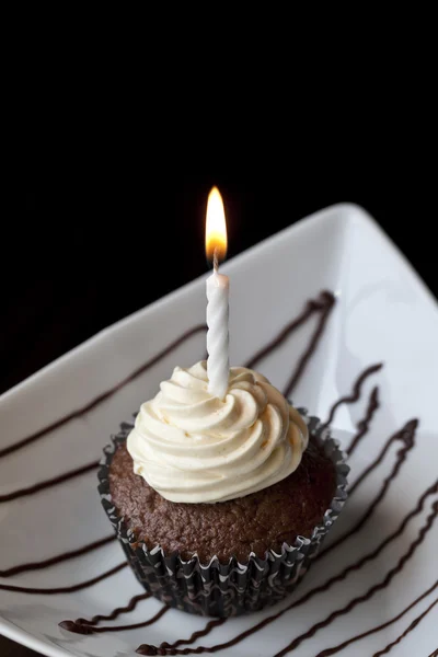 Cupcake al cioccolato con candela di compleanno ardente Immagini Stock Royalty Free