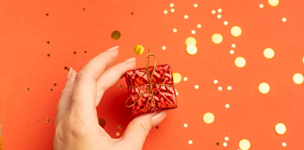 En nyårspresent i en kvinnas hand. En julklapp. Uppfattat utrymme. En artikel om att välja en gåva. — Stockfoto