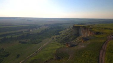 Kırım 'daki beyaz kayanın videosu. Yarımadanın etrafını dolaş. Ukrayna. Bir uçurum. Güzel dağlar. Dağ manzarası 4K. Yaz doğası. Kırım. Bir kuadrokopterin videosu. Hava videosu