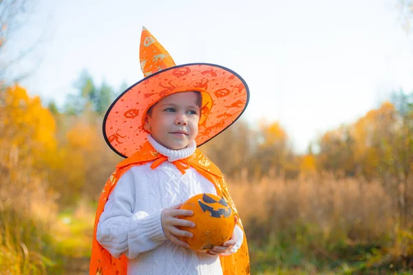 Портрет мальчика в хэллоуинской одежде с тыквой на улице. Традиционный праздник. 31 октября. — стоковое фото