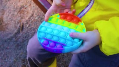 Bir çocuk anti-stres pop it oyuncağı oynuyor. Modern oyuncaklar. Stres önleyici oyuncak. Duyusal bir oyuncak. Motor beceri geliştirme. Eğilimler.