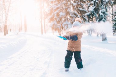 The boy throws snow with a shovel in winter lifestyle . Winter walks. An article about childrens winter leisure.